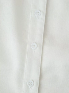 Detail view of the white cotton-linen shirt placket showing textured fabric and buttons