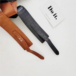 Close-up of black and brown wide waist belts with embossed crocodile leather texture