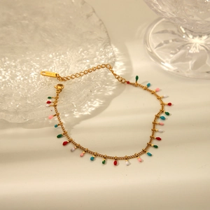 Detail of a gold bracelet featuring colorful enamel beads and adjustable lobster clasp