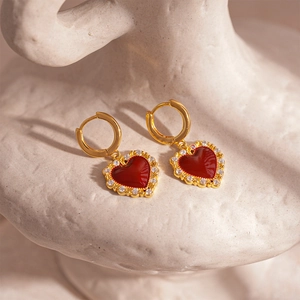 Detailed close-up of vintage gold-plated heart earrings with red enamel and zircons