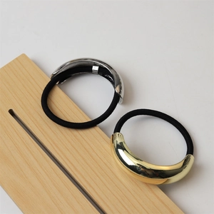 Close-up of minimalist gold and silver curved metal hair ties on wood background