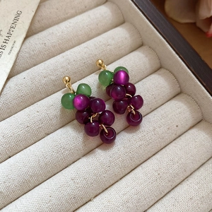 Detailed view of grape-shaped resin earrings with purple beads and green leaf accents
