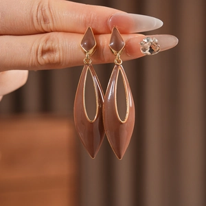 Close-up of vintage brown enamel teardrop earrings with golden metallic edges