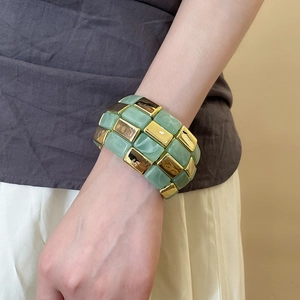 Detail of chunky acrylic and gold metal square link bracelet on a woman's wrist