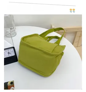 Detailed side view of green canvas tote bag with reinforced straps on white table