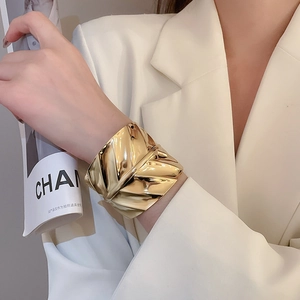 Gros plan détaillé du large bracelet doré à texture de vagues irrégulières sur un mannequin