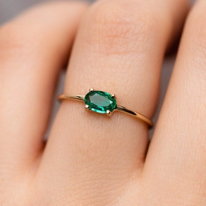 18k gold plated stainless steel ring featuring an oval emerald stone on finger