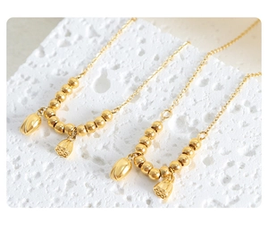 Close-up of gold beaded anklets featuring lotus pod and flower bud charms on stone