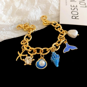 Bracciale con ciondoli dorati, stelle marine, conchiglie smaltate e perle barocche