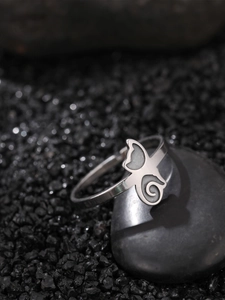 Macro shot of silver butterfly ring with spiral motif on dark stone base