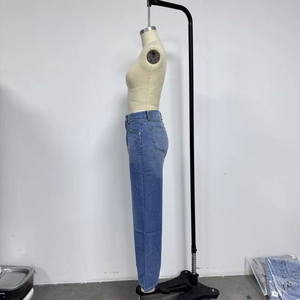 Detail of high-waisted distressed blue denim jeans with side pocket and straight leg cut