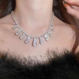 Close-up of sparkling zircon teardrop fringe necklace on model with black feather outfit
