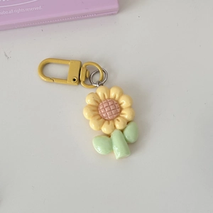 Macro shot of a sunflower keychain with yellow petals, pink core and green leaves