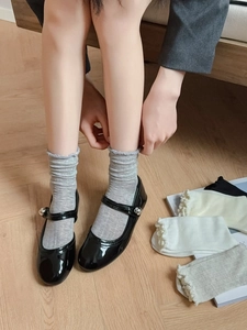 Detail view of cotton mesh socks with ruffled edges in multiple colors on wooden floor