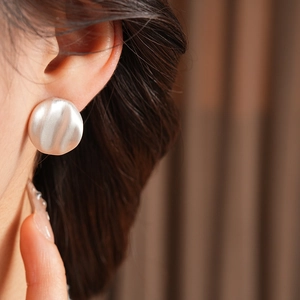 Detail of silver pleated geometric stud earrings with matte brushed metal texture