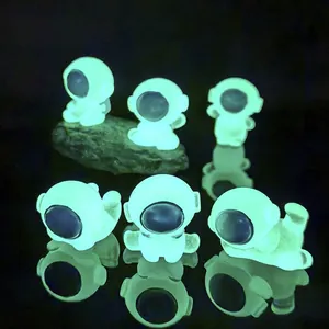 Luminous resin astronaut figurines set showing bright green glow in the dark room