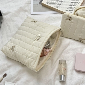 Close-up of cream quilted cosmetic bags featuring embroidered rabbits and gold labels