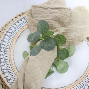 Detailed close-up of artificial eucalyptus leaf napkin ring on a beige linen napkin