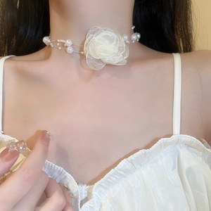 Close-up of a delicate white layered tulle flower choker with faux pearl accents on a model
