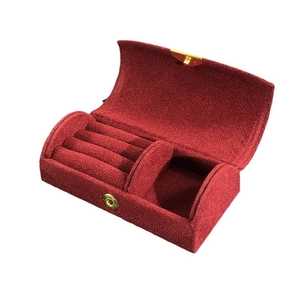 Portable deep red velvet jewelry box with gold metal clasp and interior ring slots