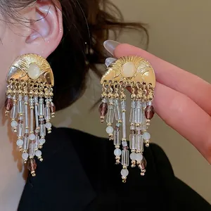 Vintage gold crystal tassel earrings with pearls and beads shown on a model