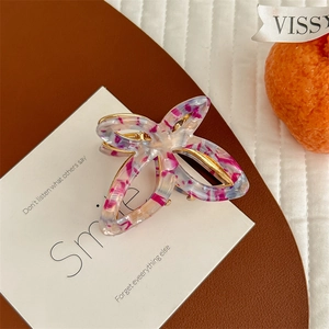 Macro detail of hollow butterfly hair claw clip with pink purple patterns and gold frame