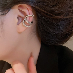 Close-up of three silver-toned ear cuffs featuring cubic zirconia on a model's ear