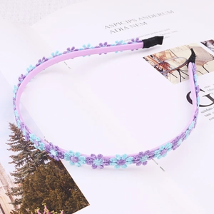 Detail of purple daisy headband with blue woven flowers on a magazine background