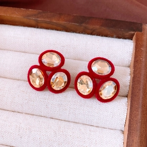 Detailed close-up of retro oval earrings with champagne gems and red velvet trim