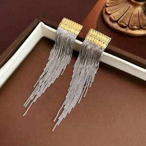 Détail de boucles d'oreilles pompons argentées avec pierres en zircon jaune rectangulaires
