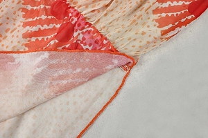 Close-up of vibrant orange abstract print mesh fabric with detailed edge stitching