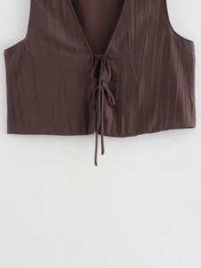 Détail du gilet plissé marron foncé avec laçage frontal élégant et texture de tissu raffinée