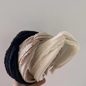 Close-up of three layered wide hairbands in black, champagne, and cream tweed