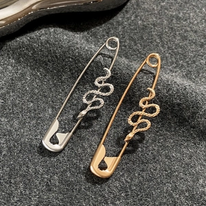 Dettaglio macro di orecchini a spilla da balia a forma di serpente oro e argento