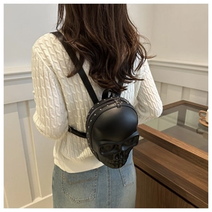 Rear view of a black 3D skull backpack with silver rivets worn by a model in a room