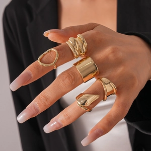 Close-up of five-piece chunky gold geometric irregular rings on a hand with manicure