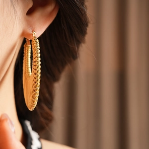 Close-up of gold oversized textured hoop earrings with a stylish vintage woven design