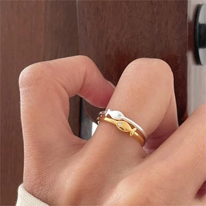 Dettaglio di anelli a pesce in argento e oro con zirconi sul dito di una modella