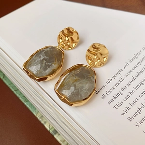 Détail de boucles d'oreilles en résine vintage avec texture marbre gris sur un livre