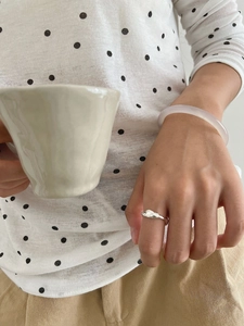 Close-up of a silver wavy ring and translucent pink resin bangle on a female hand