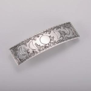 Macro detail of vintage alloy hair clip featuring embossed moon phases and forest patterns