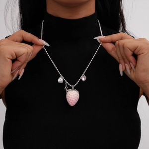 Detailed view of pink strawberry pendant necklace with rhinestones on black sweater