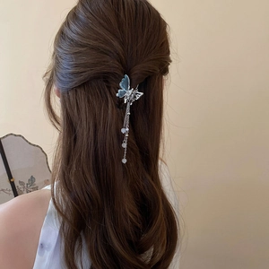 Détail de la pince papillon en métal avec ailes bleues et longs glands de perles