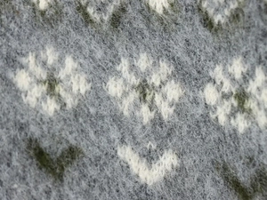 Detailed macro view of soft fuzzy grey knit fabric with white snowflake jacquard pattern