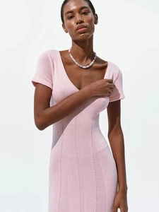 Close-up of pink V-neck knitted dress showing detailed ribbed texture and soft fabric