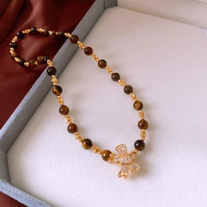 Detail of tiger eye bead necklace with a gold butterfly pendant and zircon stones