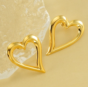 Detailed close-up of gold hollow heart earrings featuring a polished mirror finish surface