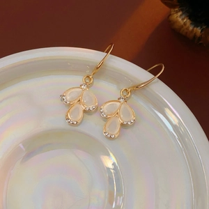 Detail of teardrop opal earrings with crystals on a pearlescent white decorative dish