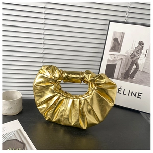 Detailaufnahme einer goldglänzenden Faltenhandtasche mit moderner metallischer Textur