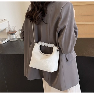 Detail of white lychee leather dumpling bag with pearl handle and silver chain strap